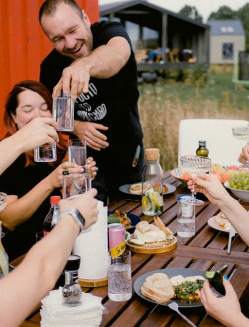 A joyful outdoor gathering with friends clinking glasses over a shared meal.